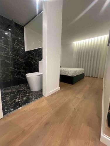 a bathroom with a toilet and a bed in a room at Chez Alexandre - Magnifique Appartement - Ponte de Lima - Wifi Gratuit - Parking Gratuite in Cancinhola