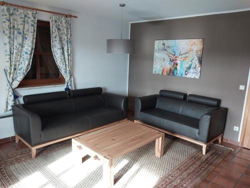 a living room with two black couches and a coffee table at Ferienhaus Kraxlhütte Kärnten in Velden am Wörthersee