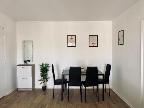 een eetkamer met een tafel en zwarte stoelen bij Cocoon citadin : Appartement 2 pièces au coeur d'Evry in Évry-les-Châteaux
