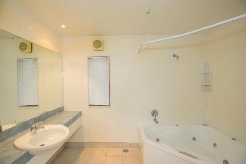 a white bathroom with a tub and a sink at Albany Executive Motor Inn Limited in Auckland