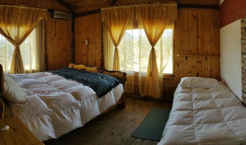 a bedroom with a bed and two windows with curtains at Hostería Lago Cinco in Río Pico