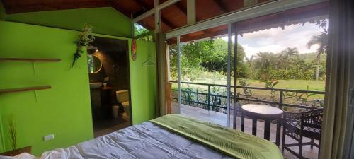 a green room with a bed and a balcony at Casita Maripier Colón 