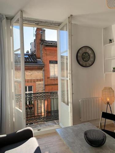 - un salon avec une porte ouverte sur un balcon dans l'établissement Lumineux appartement Capitole plein centre, à Toulouse