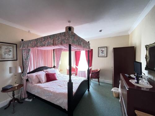 a bedroom with a canopy bed and a desk at White Court Llandudno in Llandudno