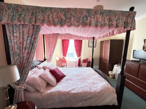 a bedroom with a canopy bed and pink curtains at White Court Llandudno in Llandudno