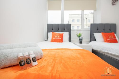 um quarto com 2 camas individuais e almofadas laranja em Hephaestus Apartment - The Craftsman of Town em Southampton
