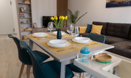 a dining room table with glasses and yellow flowers on it at 'Just like home' Apartment - with Private Parking Place in Galaţi