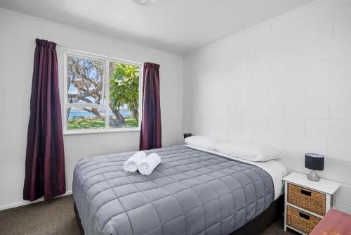 1 dormitorio con 1 cama con 2 toallas en The Sands Motel en Tutukaka