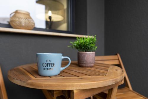 a coffee cup sitting on a wooden table with a plant at 'Just like home' Apartment - with Private Parking Place in Galaţi