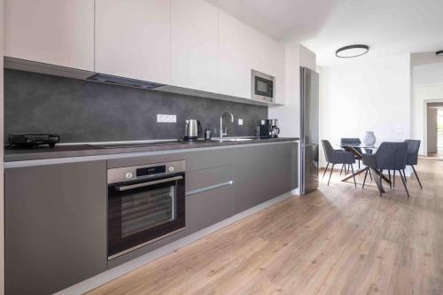 a kitchen with stainless steel appliances and a table with chairs at SeaLife Grand Penthouse Varkiza in Vari