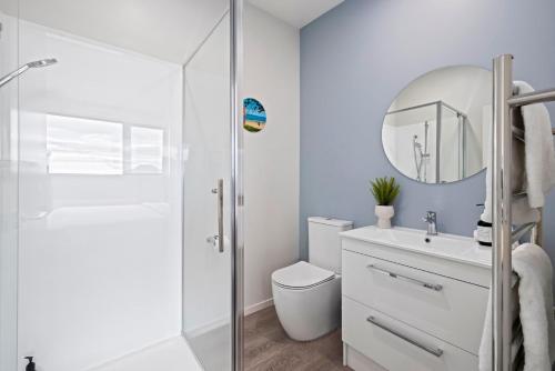 a bathroom with a toilet and a sink and a mirror at Seaside Serenity at Bask Retreats in Mount Maunganui