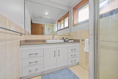 a white bathroom with a sink and a shower at Ocean Breeze Vincentia by Book Jervis Bay in Vincentia