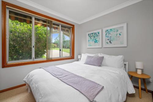 a white bedroom with a large bed and a window at Ocean Breeze Vincentia by Book Jervis Bay in Vincentia