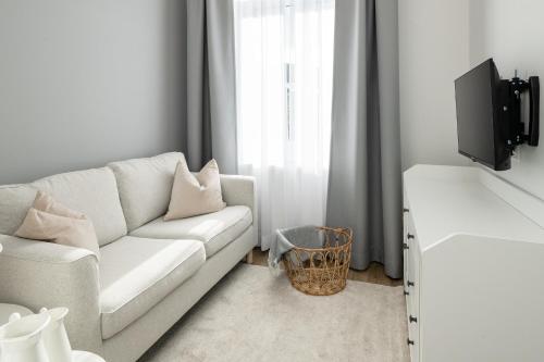 a living room with a white couch and a tv at Hotel Markt 5 - inmitten der Lübbecker Altstadt, kostenloser Parkplatz direkt am Hotel in Lübbecke