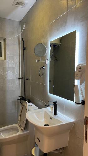 a bathroom with a sink and a toilet and a mirror at جادا للشقق المخدومة Jada in Al Khobar