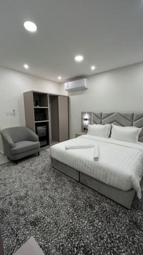 a large bedroom with a large bed and a chair at جادا للشقق المخدومة Jada in Al Khobar