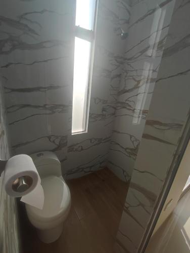 uma casa de banho com um WC, uma janela e um chuveiro em Apartments em Chiclayo