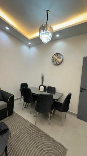 a dining room with a table and chairs and a clock at Luxury 2 bedroom new brand in Ajman 