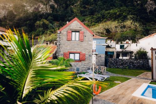 a stone house with red doors and a yard at Casas do Calhau Miúdo - Seixal in Seixal
