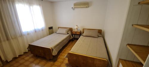 2 camas en una habitación pequeña con ventana en Villa Rumipal alquiler temporario! en Villa Rumipal