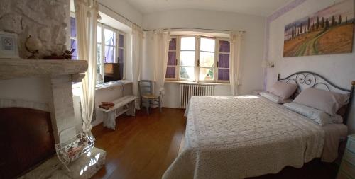 1 dormitorio con cama blanca y chimenea en Casale vita nova, en Manciano