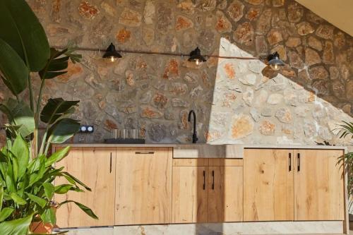 uma cozinha com armários de madeira e uma parede de pedra em Luxuriöse Villa mit Pool nahe Canyamel em Capdepera