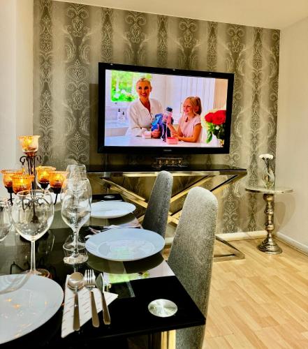 a dining room with a table and a tv on a wall at NewDay Property - Chelsea in London