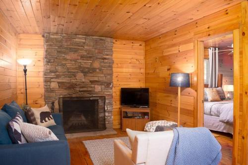 a living room with a stone fireplace in a cabin at Nantahala Resort cabin, POOL OPEN, horseback riding, game room, gym, restaurant on site in Bryson City