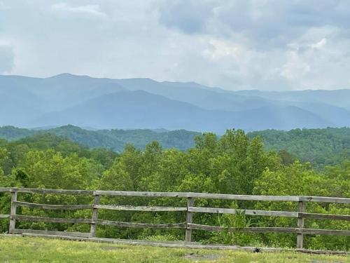 a wooden fence in a field with mountains in the background at Nantahala Resort cabin, POOL OPEN, horseback riding, game room, gym, restaurant on site in Bryson City