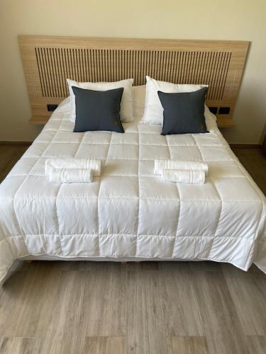 a large bed with white sheets and blue pillows at La Morada Almafuerte in Almafuerte