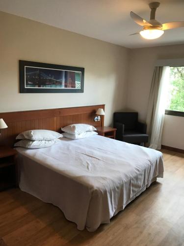 a bedroom with a large white bed and a chair at Flat em Gramado in Gramado