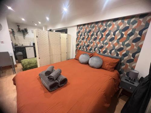 a bedroom with a bed with orange sheets and pillows at Nice StudioFLAT in London in London