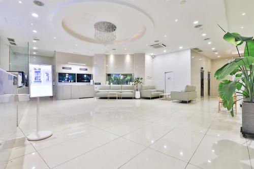 a large white lobby with white furniture and a large chandelier at Shire Hotel Seomyeon in Busan