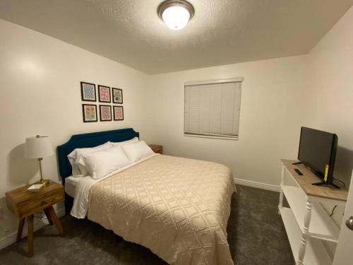 um quarto com uma cama e uma secretária com uma televisão em Snug Home with fenced yard em West Valley City