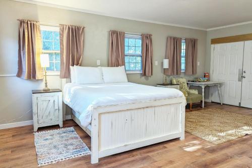 a bedroom with a white bed with a desk and windows at The Garden House of Downtown Manitou Springs in Manitou Springs