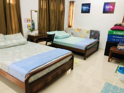 a bedroom with two beds and a chair and a table at Homey Stopover Cherating in Kuantan