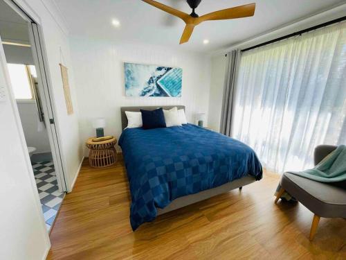 a bedroom with a blue bed and a window at Tide 'n' Seek: Family Beach House with Games Room in Vincentia