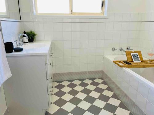 a white bathroom with a checkered floor at Tide 'n' Seek: Family Beach House with Games Room in Vincentia