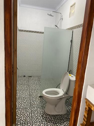 a bathroom with a toilet and a shower at Gamat Garden Homestay in Nusa Penida