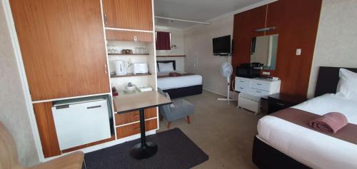 a hotel room with two beds and a desk at Mayfair Court Motel in Tokoroa