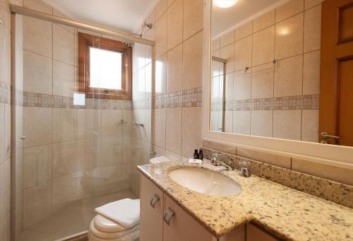 uma casa de banho com um lavatório, um WC e um espelho. em LOCAR-IN GRAMADO - Duplex Solar da Borges em Gramado
