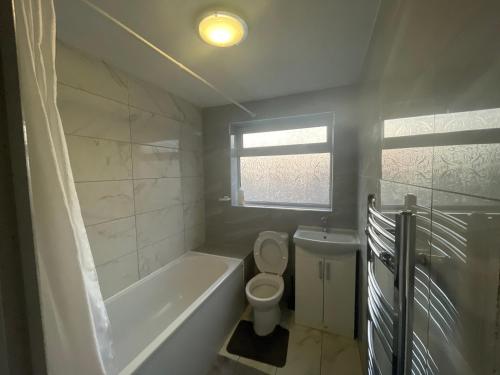 a bathroom with a tub and a toilet and a sink at Bowman’s Place Cosy Lodge in Kent