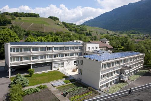 an aerial view of a white building with a mountain at Hôtellerie Franciscaine in Saint-Maurice