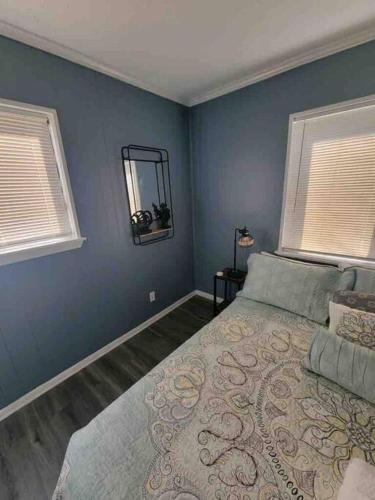 a blue bedroom with a bed and two windows at 2022 Renovated 2-bdrm cozy, lovely condo w/parking! in Hilton Head Island