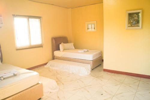 a room with two beds in a room with yellow walls at Hana-Natsu Resorts Pool & Hotel in Maybayo