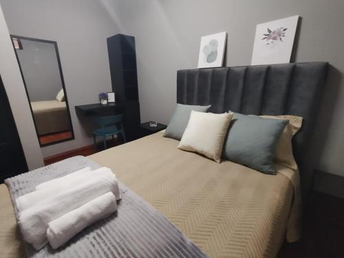 um quarto com uma cama com uma cabeceira e almofadas pretas em La Casona Hostel em Cochabamba