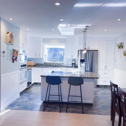 a kitchen with white cabinets and two bar stools at Quiet Three Bedrooms House in Victoria