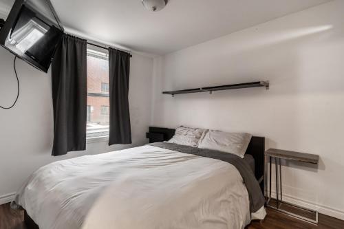 ein Schlafzimmer mit einem Bett und einem TV an der Wand in der Unterkunft Cozy 2 Bedroom Apartment - 1902 in Montreal