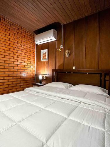 un grande letto bianco in una stanza con un muro di mattoni di Casa de campo com cachoeira no quintal a Gaspar