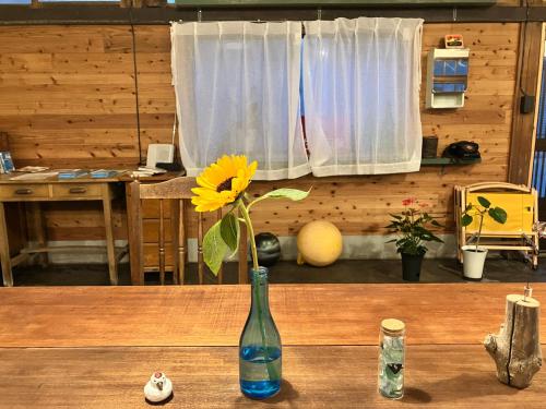 a vase with a yellow flower in it on a table at Stay Do in Oshima
